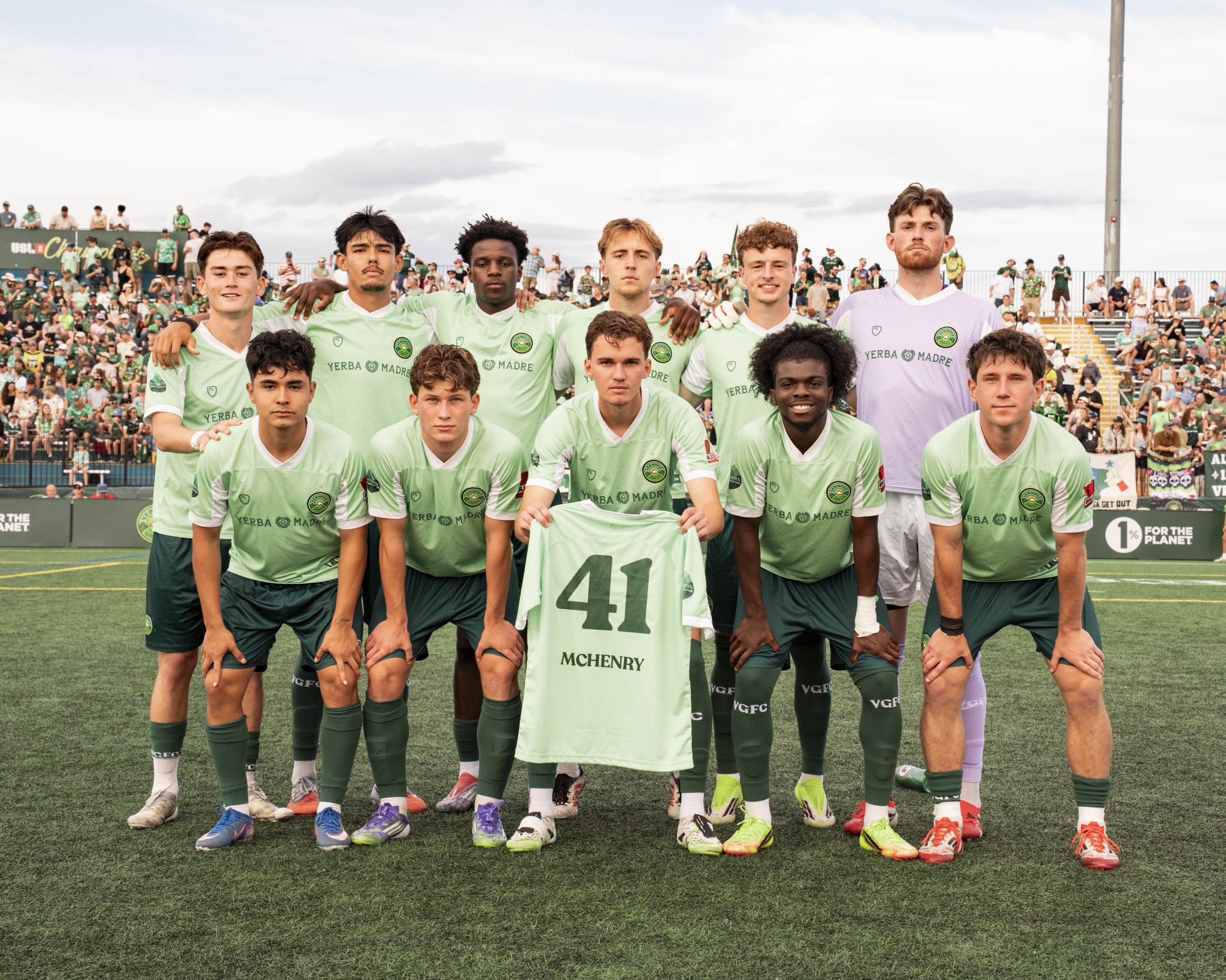 A soccer team holding up a green number 41 McHenry jersey in tribute to Zach