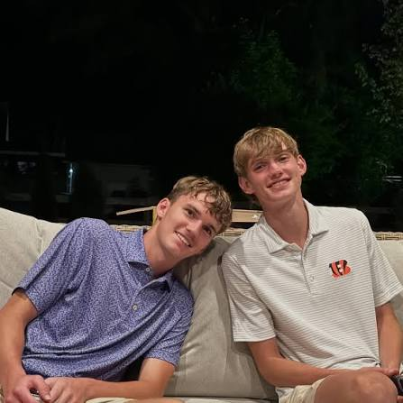 Zach smiling with a friend on an outdoor couch in the evening
