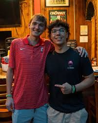 Zach with a friend, arms around each other, smiling together