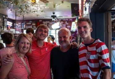 Zach with family and friends smiling together at a pub